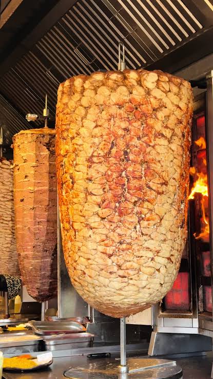 Frische Dönerspieße am vertikalen Grill mit offenen Flammen